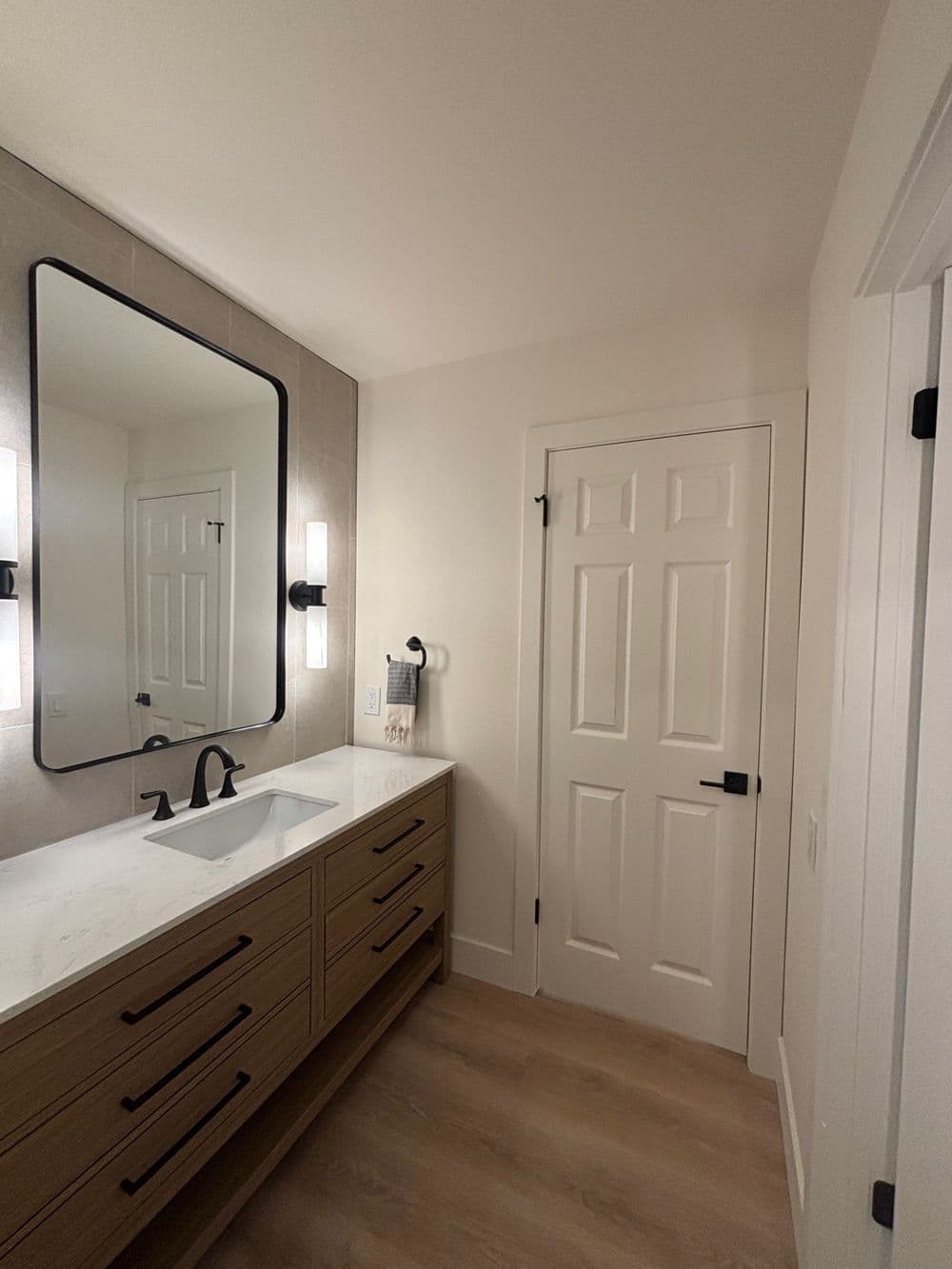 Modern bathroom design featuring a wooden vanity, sleek mirror, and stylish lighting.